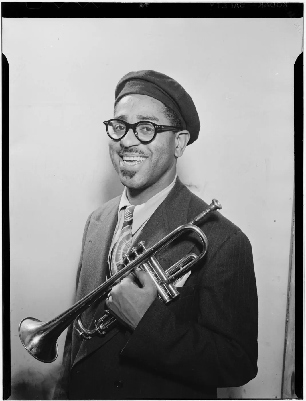Dizzy Gillespie wearing a beret and glasses with his trumpet
