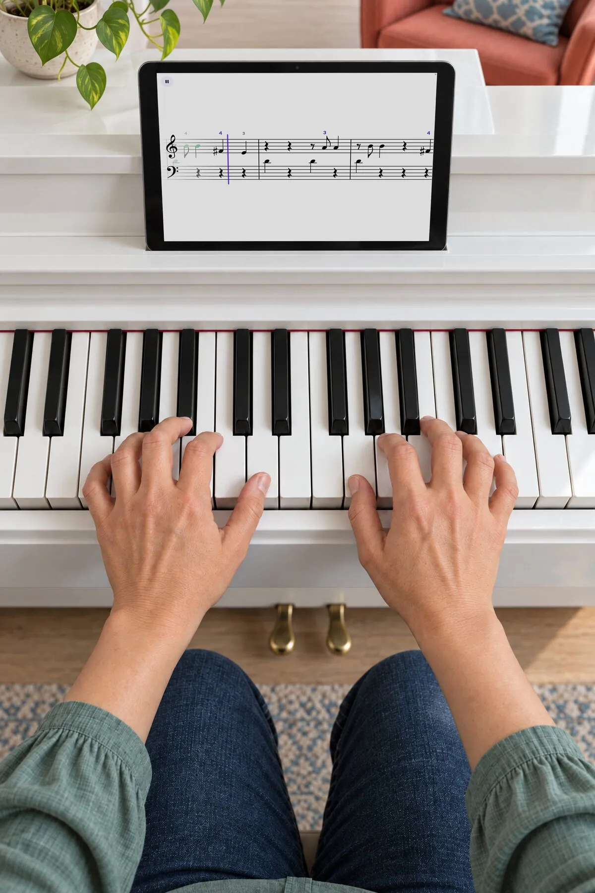 Dos manos sobre las teclas de un piano digital blanco y, encima, la partitura en una tablet