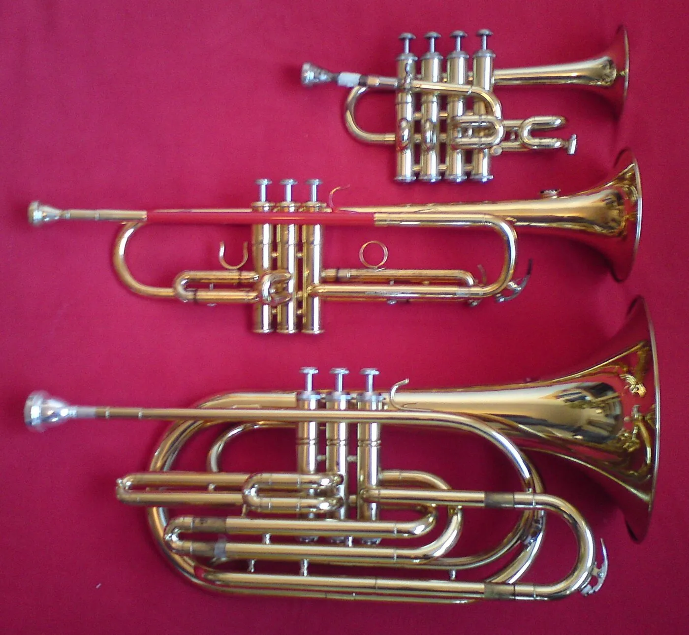 Piccolo trumpet, standard B♭ trumpet and bass trumpet shown side by side